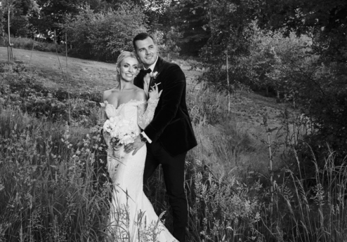 A couple in wedding attire embrace in a lush garden at Fernhill House Hotel.
