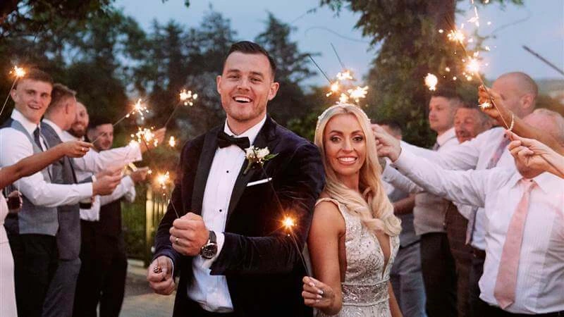 A joyful couple surrounded by family holding sparklers at Fernhill House Hotel wedding.