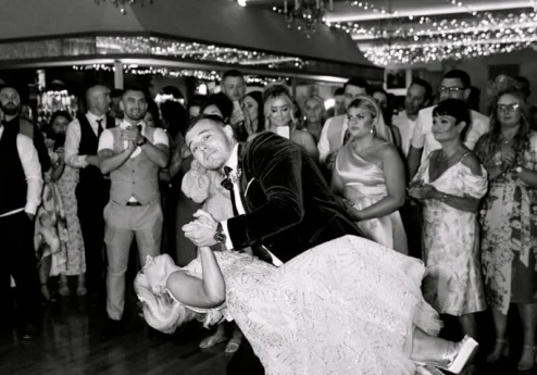 Couple dancing joyfully at a wedding under twinkling fairy lights at Fernhill House Hotel.