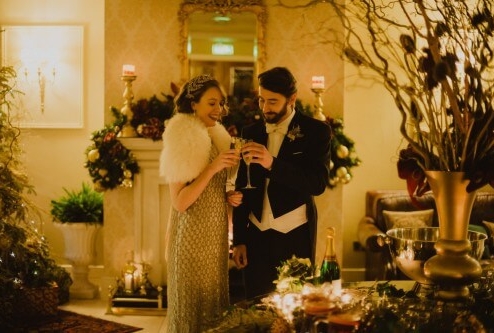 Elegant couple enjoying a festive toast in a warm, beautifully decorated hotel lounge.