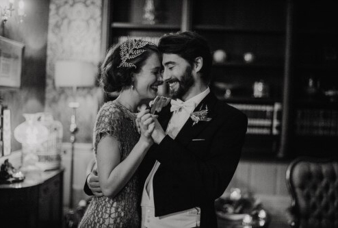 A couple dances joyfully in a cosy, vintage-style hotel lounge.