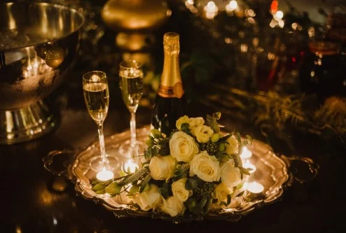 Elegant table with champagne, candles, and white roses, creating a romantic atmosphere.