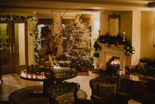 Festive hotel lounge with decorated Christmas tree and cosy fireplace.