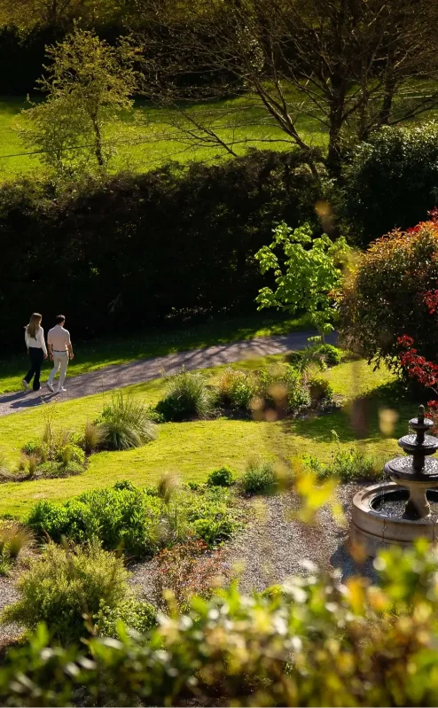 Couple strolling through lush gardens at Fernhill House Hotel.