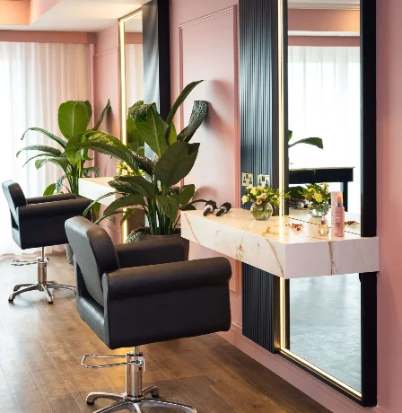 Cosy salon space with elegant seating, mirrors, and greenery.