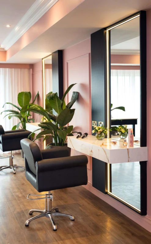 Cosy salon space with elegant seating, mirrors, and greenery.