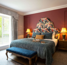 Cosy hotel room with large bed, floral headboard, and tray of refreshments.