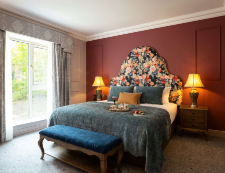 Cosy hotel room with large bed, floral headboard, and tray of refreshments.