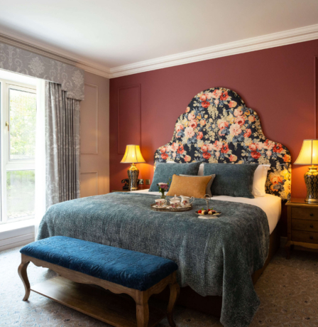 Cosy hotel room with large bed, floral headboard, and tray of refreshments.
