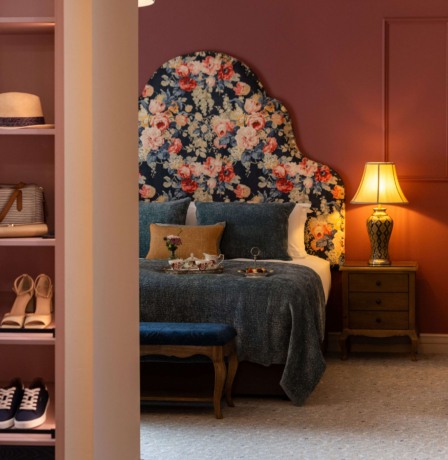 Cosy hotel room with a floral headboard, inviting bed, and warm lighting for relaxation.