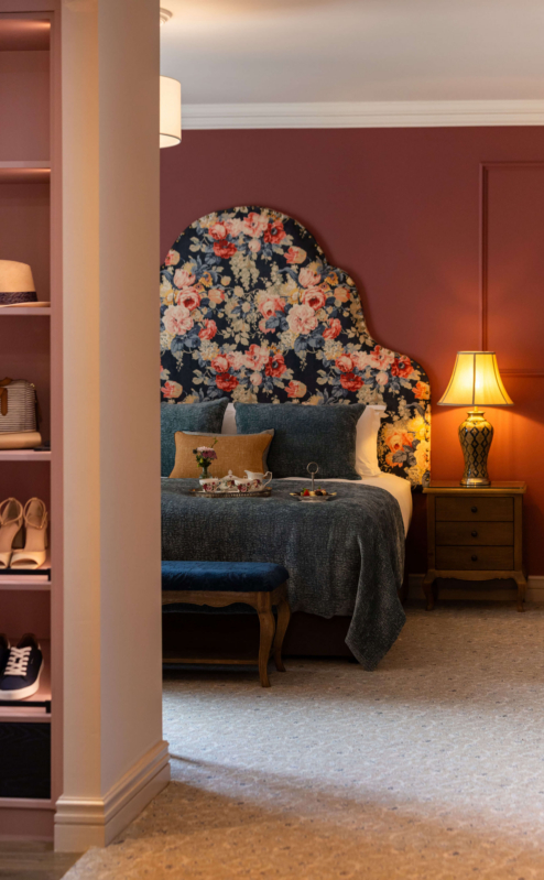 Cosy hotel room with a floral headboard, inviting bed, and warm lighting for relaxation.