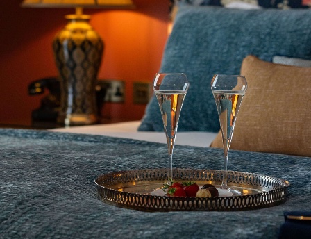 Elegant hotel bedroom setting with glasses of champagne and a cosy atmosphere.