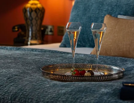 Cosy bedroom setting with champagne, warm lighting, and elegant floral decor.