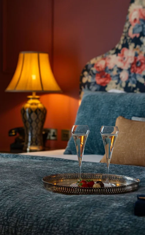 Cosy bedroom setting with champagne, warm lighting, and elegant floral decor.