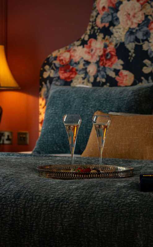 Luxurious hotel room with elegant decor and champagne on the bed.