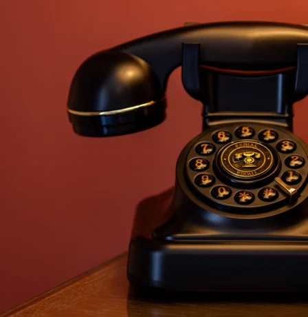 Vintage rotary phone on wooden table against a warm red wall at Fernhill House Hotel.