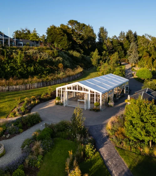 A serene garden setting with a glasshouse under clear blue skies at Fernhill House Hotel.