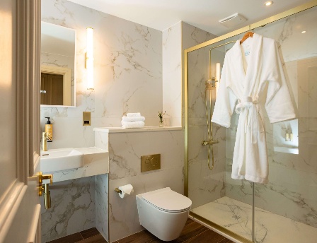 Elegant hotel bathroom with a marble finish and a hanging robe.