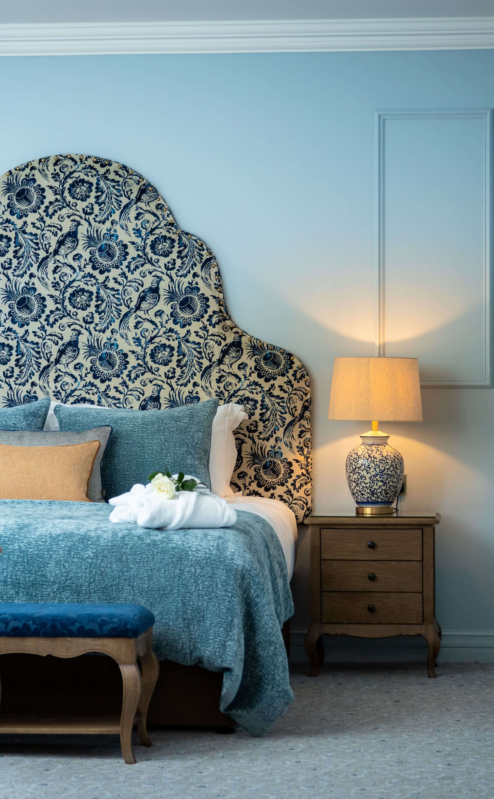 Elegant hotel room with ornate headboard and warm lighting, creating a cosy atmosphere.