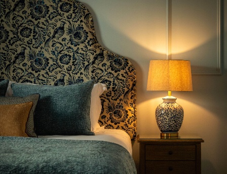 Elegant hotel room with soft lighting and stylish decor, featuring a beautifully adorned bed.