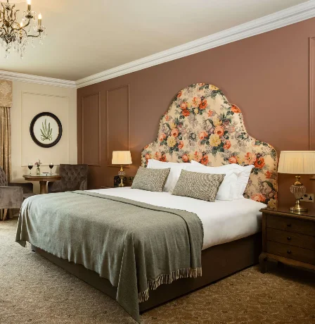 Cosy hotel room with country view, plush bed, seating area, and elegant decor.