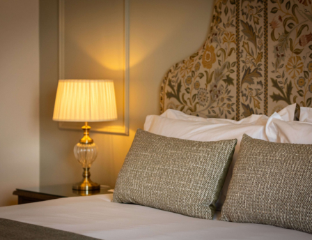 Cosy hotel room with elegant bedding and soft lamp lighting.