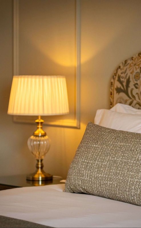 Cosy hotel room with elegant bedding and soft lamp lighting.