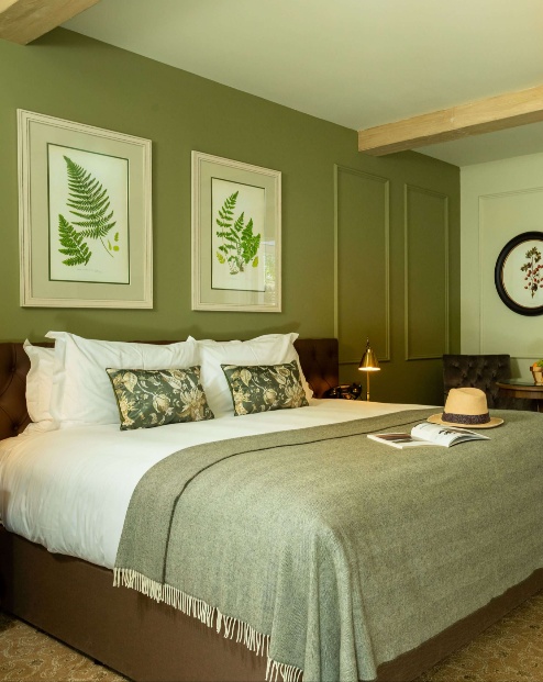 Elegant hotel room with a luxurious bed, open doors to a sunny patio garden.