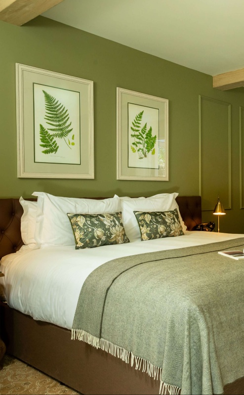 Elegant hotel room with a luxurious bed, open doors to a sunny patio garden.