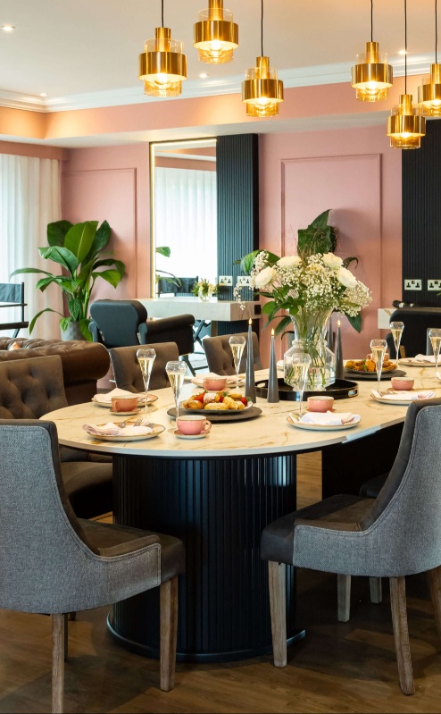 Elegant dining area with round table, plush chairs, and warm lighting at Fernhill House Hotel.