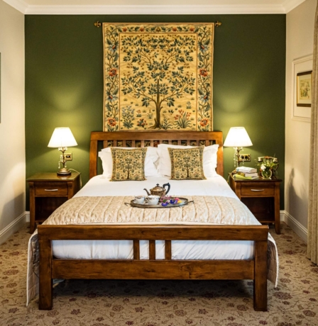 Cosy hotel room with double bed, elegant tapestry, and warm lighting.