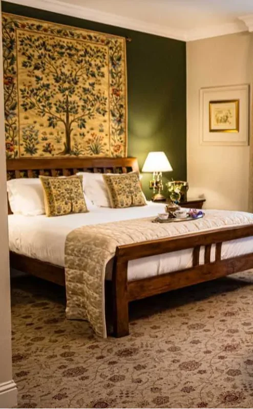 Elegant hotel room with double bed, seating area, and warm decor.