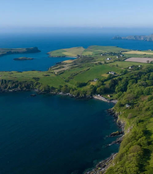 Scenic coastal view with lush green fields and blue seas.