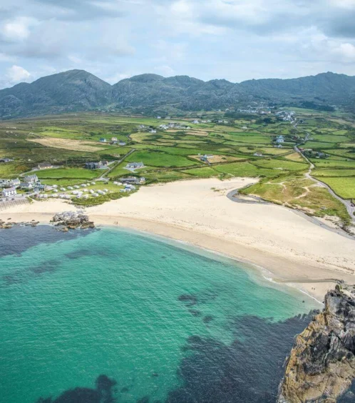 Aerial view of a lush green landscape meeting a sandy beach and turquoise sea.