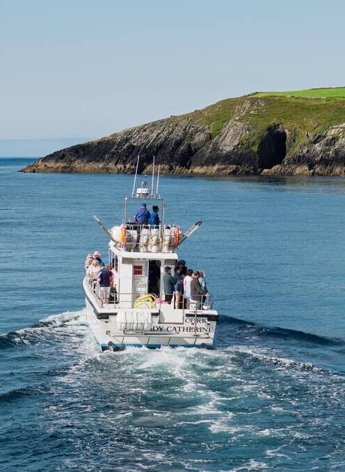 A family on a boat exploring the scenic coastline near Fernhill House Hotel, West Cork Ireland