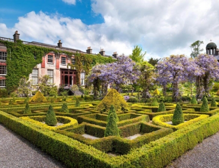 Family exploring lush gardens of Fernhill House Hotel, trimmed hedges, and blooming wisteria.