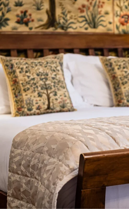 Cosy hotel bedroom with a wooden bed, soft pillows, and warm lighting at Fernhill House.