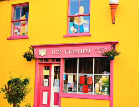 A colourful yellow ice cream and coffee shop with pink accents, exuding a welcoming charm.