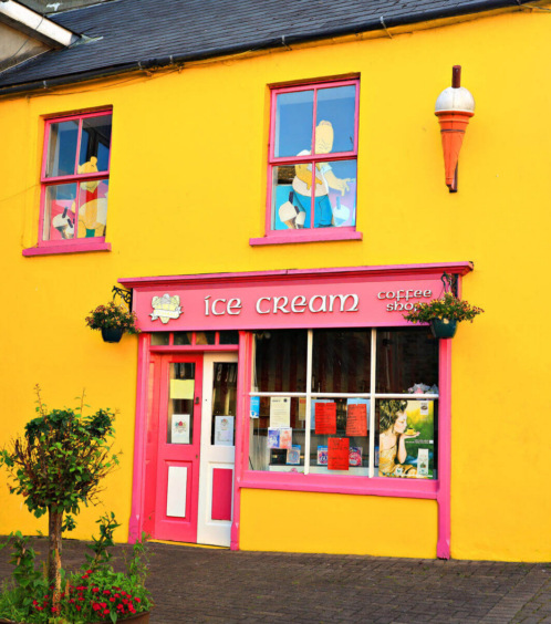 A colourful yellow ice cream and coffee shop with pink accents, exuding a welcoming charm.