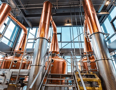 Copper distillation tanks in a well-lit modern distillery space.
