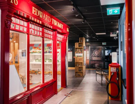 Visitors exploring a cosy hotel corridor with a vintage red storefront display.