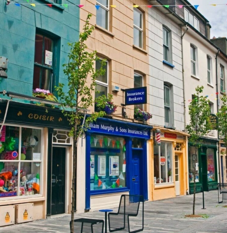 Colourful shops and quaint street in welcoming town setting.