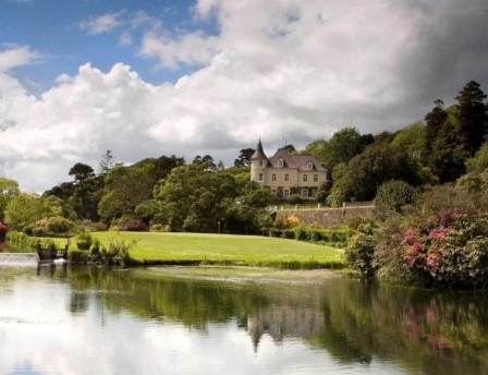 Scenic view of Fernhill House Hotel surrounded by lush gardens and tranquil pond.
