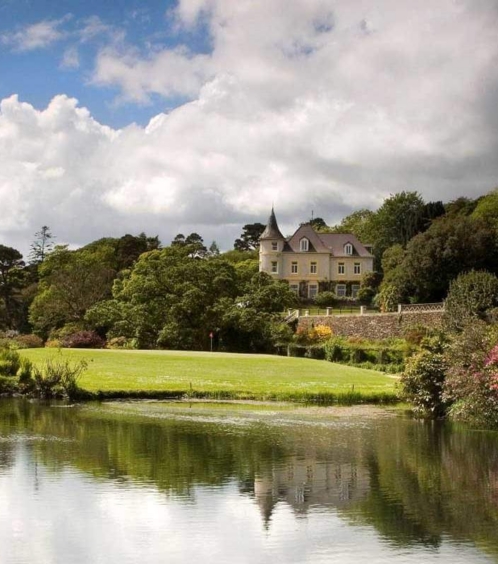 Scenic view of Fernhill House Hotel surrounded by lush gardens and tranquil pond.