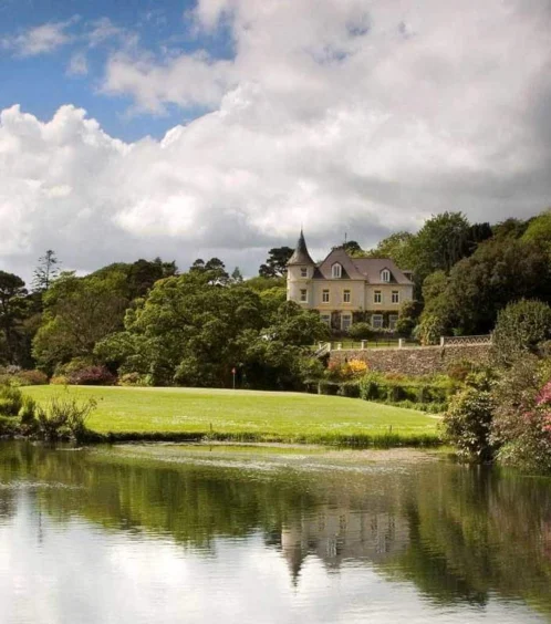 Serene garden view of Fernhill House Hotel with lush greenery and tranquil pond.