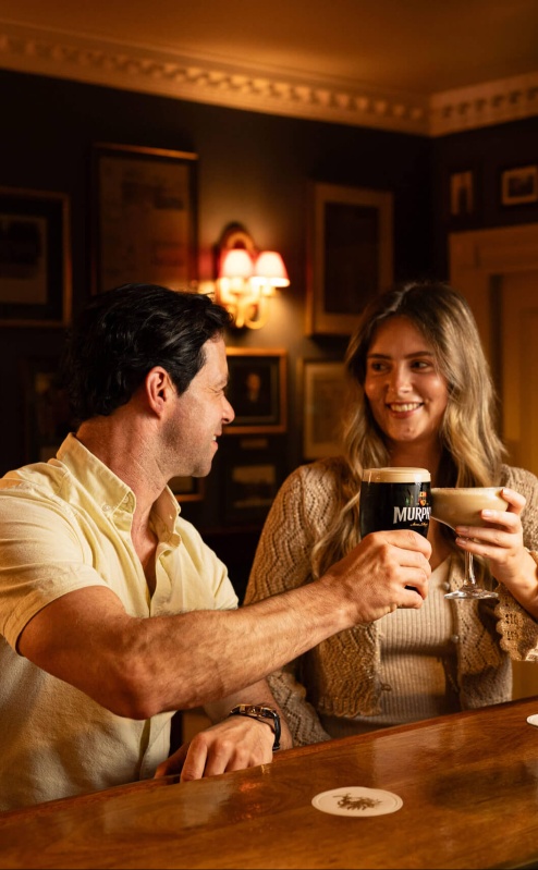 Smiling couple enjoying drinks at cozy Fernhill House Hotel bar.