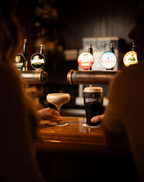 A couple enjoying drinks at a cosy hotel bar with a selection of beers on tap.