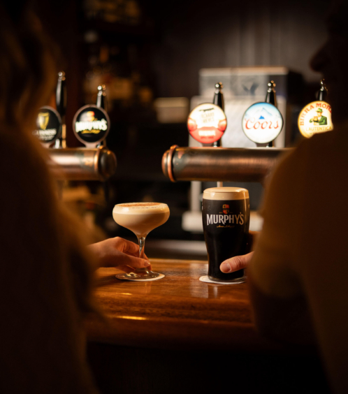 A couple enjoying drinks at a cosy hotel bar with a selection of beers on tap.