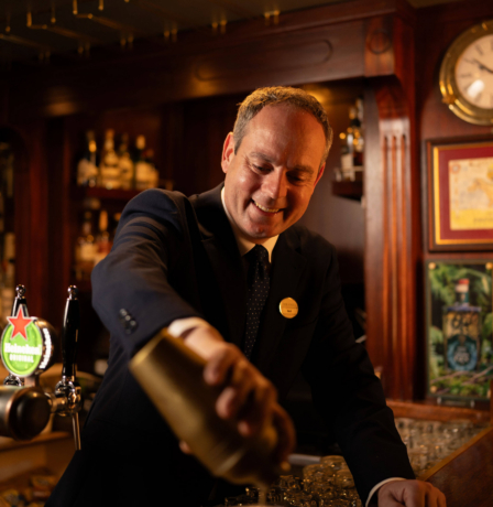 Friendly bartender expertly pouring a drink at Fernhill House Hotel bar.
