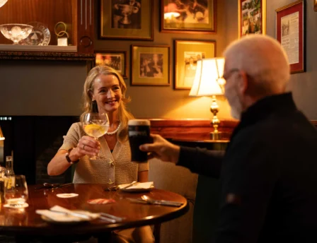 A couple enjoying drinks at Fernhill House Hotel's cosy, warmly-lit dining area.